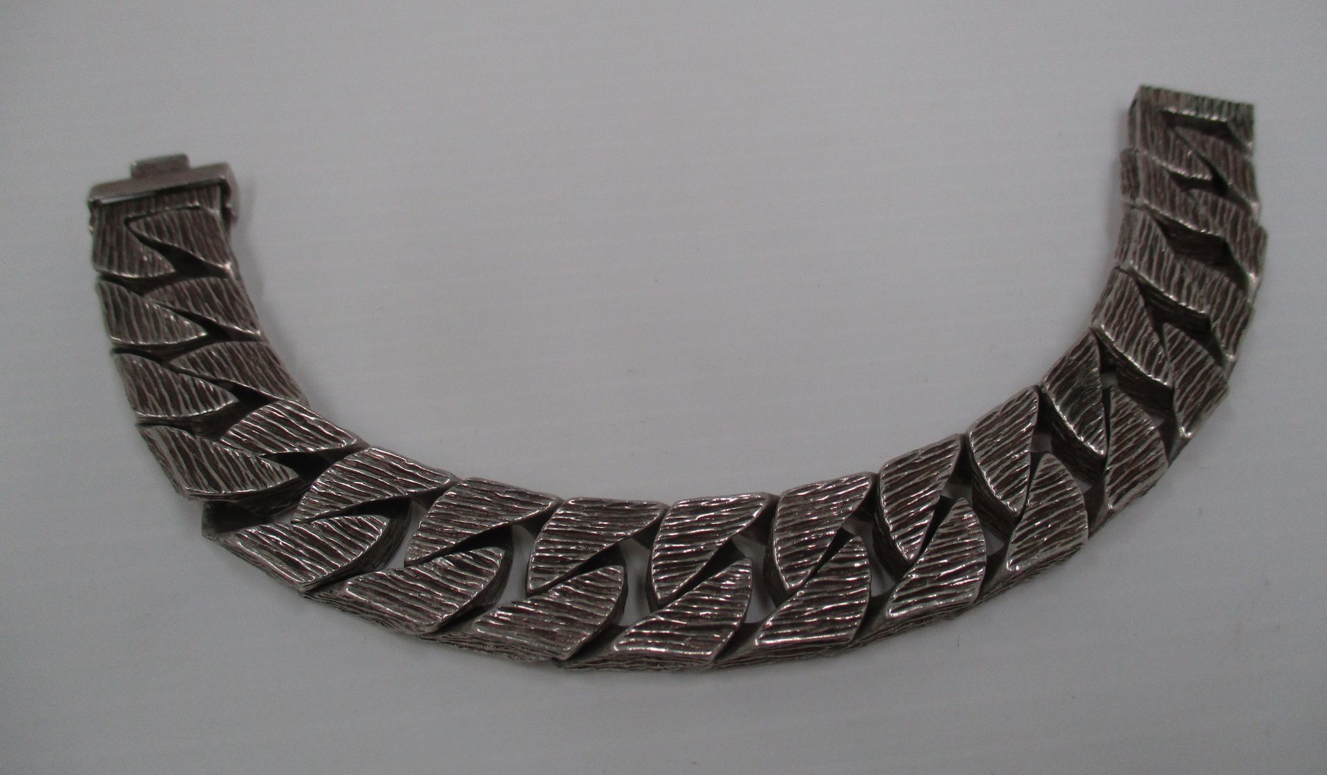 A gentleman's silver bracelet of flattened bark effect curb links [approximate weight 3.1oz].