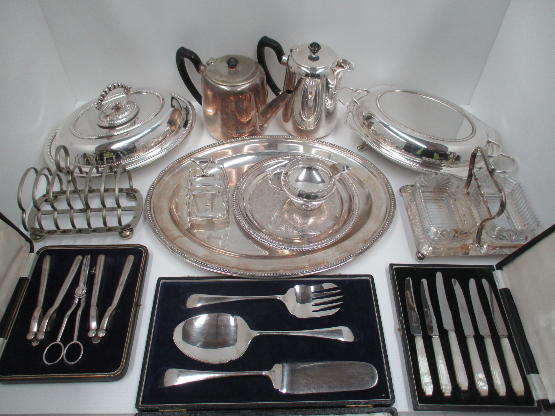 An oval silver plated serving plate, hotel plate, tea and water pots, two toast racks,