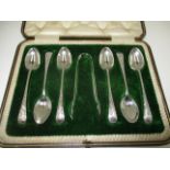 A set of six silver Old English pattern coffee spoons and tongs with floral engraved handles,