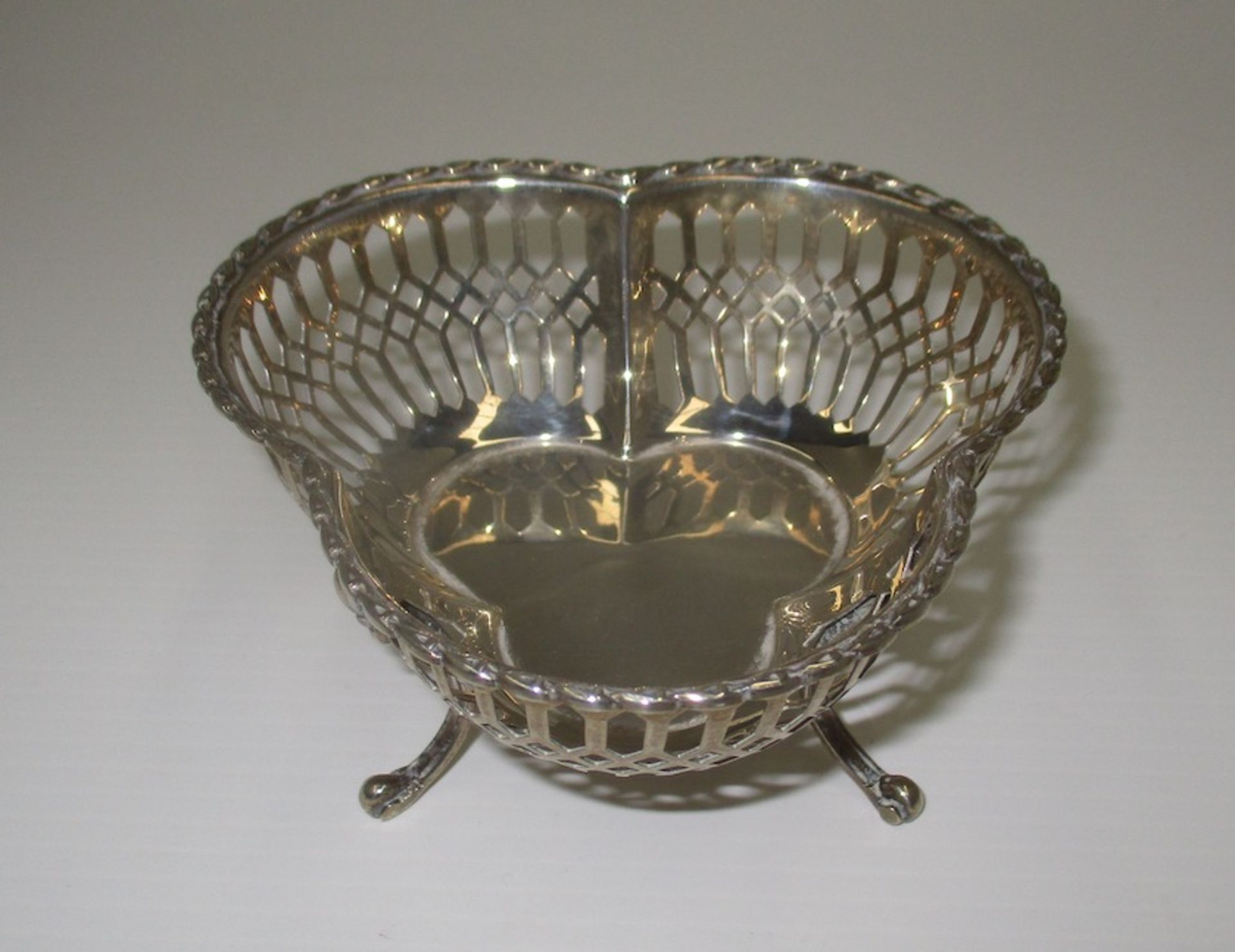 A silver tri-lobe bowl with moulded rim and pierced sides, on three scroll feet, Birmingham 1909,