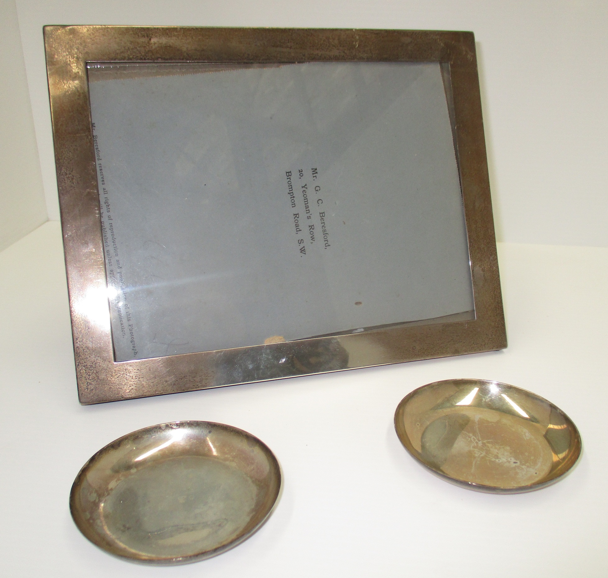 A plain rectangular silver photograph frame [aperture 20 cm x 15 cm] and a pair of silver coasters