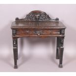 An oak side table, the raised back and drawer front with carved lion masks,