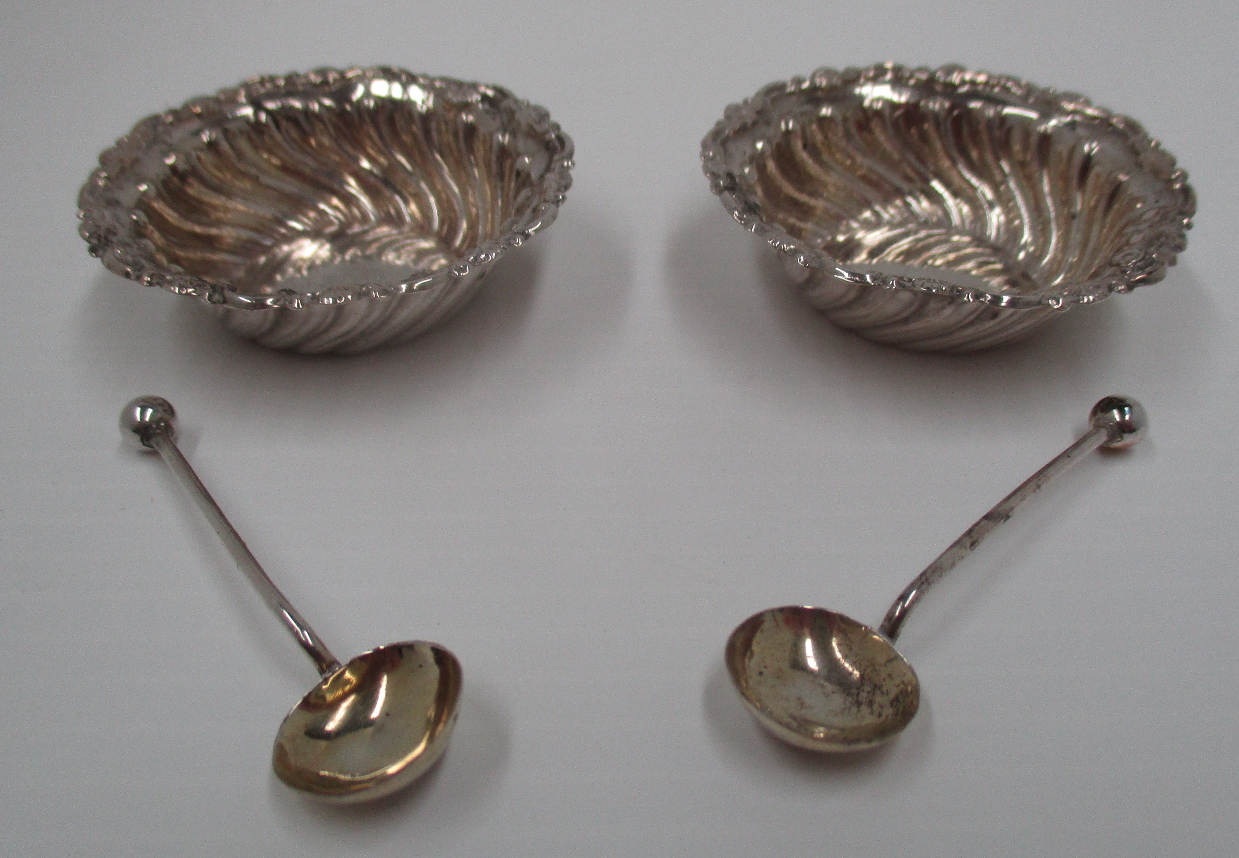 A pair of Victorian circular silver salts with wrythen embossed sides and scroll border and