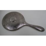 A circular hand mirror with hammered finish, silver back and cased handle.