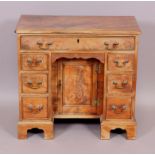 An Early George III style knee hole desk with frieze drawer over a recessed panel door cupboard,