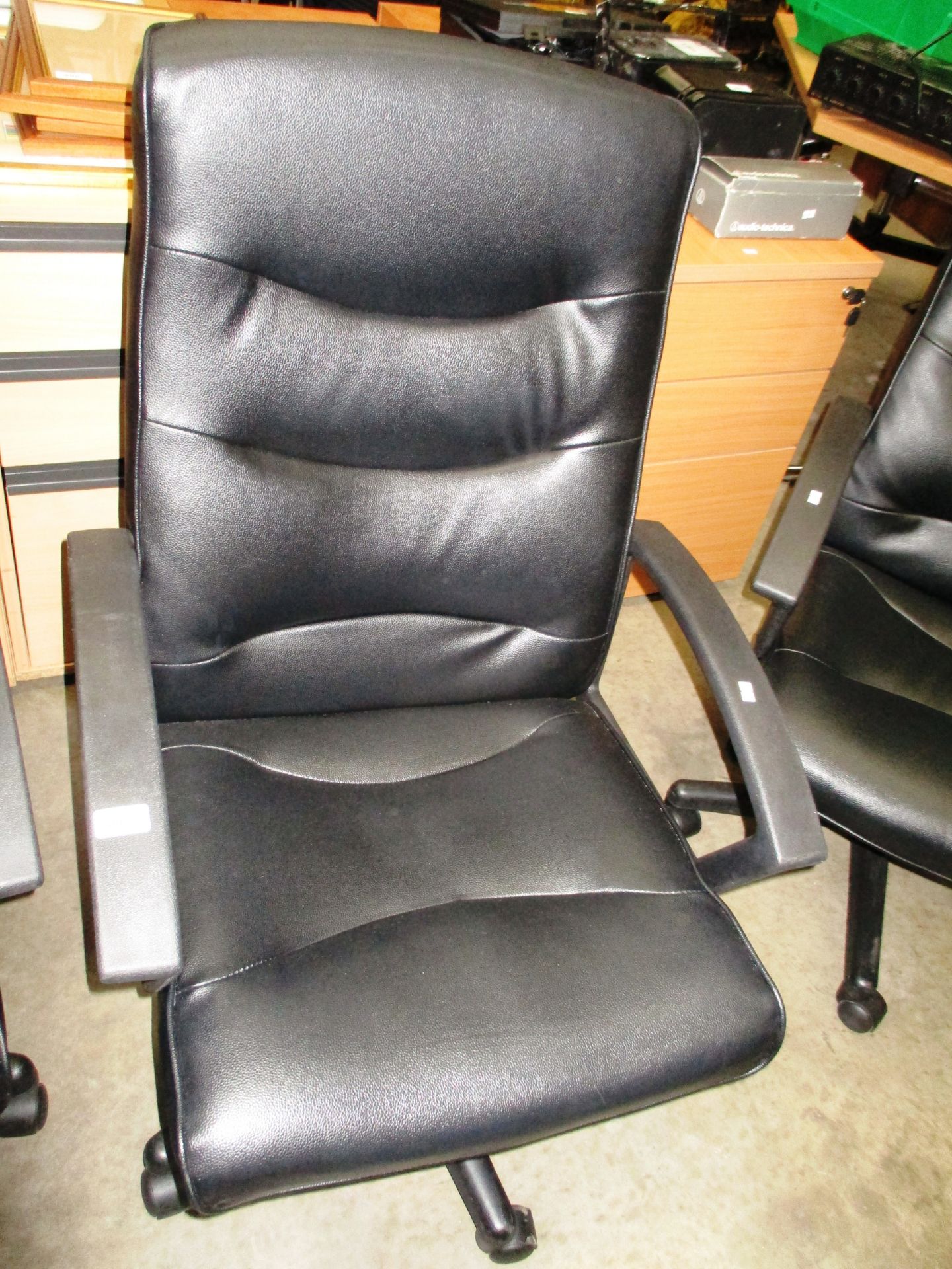 A black vinyl upholstered high back swivel armchair