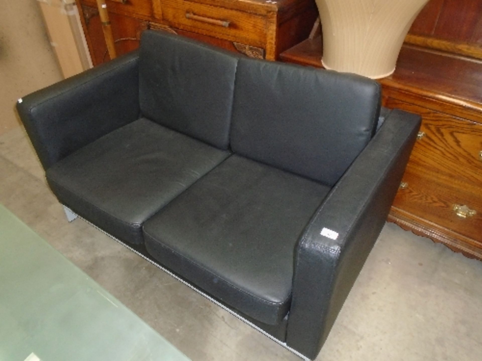 A black leather finish two seater sofa on grey metal feet