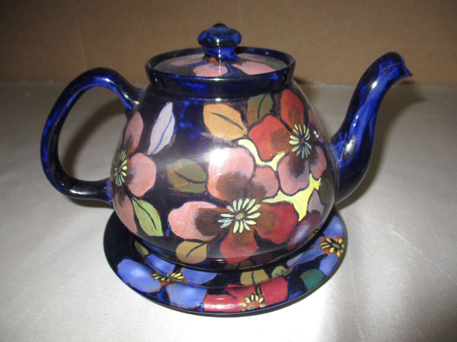 A Royal Stanley terracotta teapot and stand enamelled in floral pattern (2)