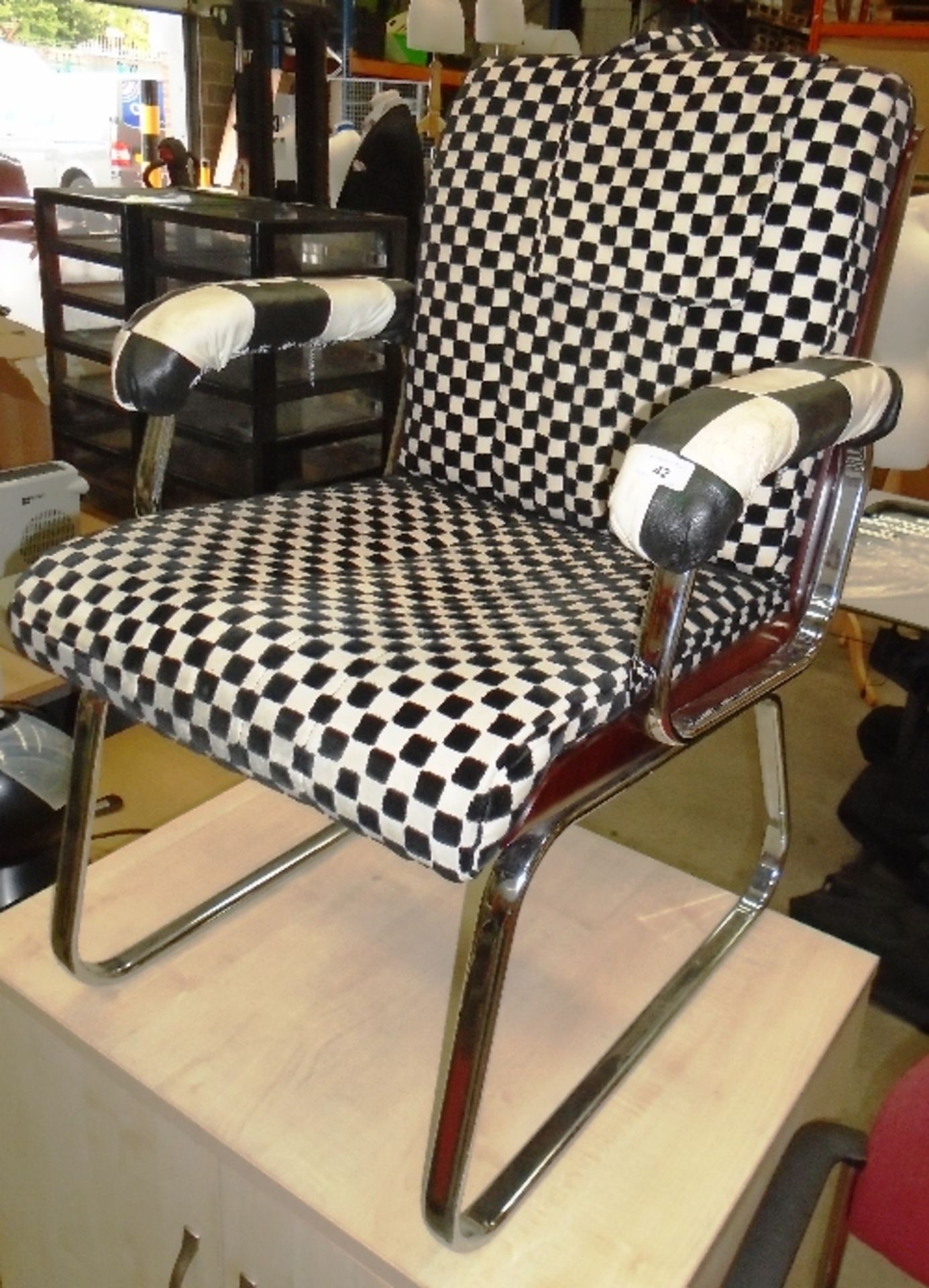 A retro style black and white checked upholstered armchair on chrome feet