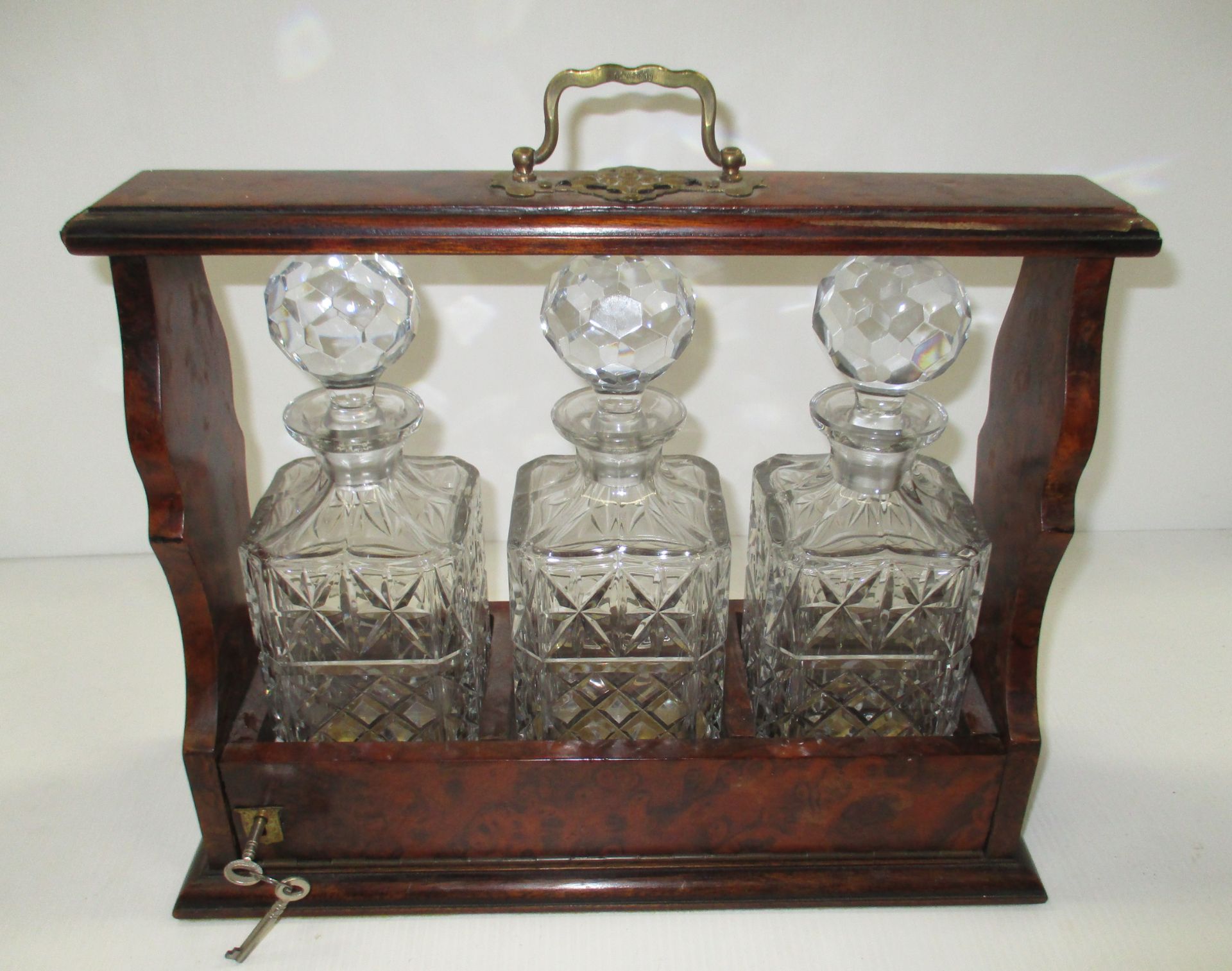 A walnut cased 3 bottle tantalus c/w 3 glass decanters and tops.