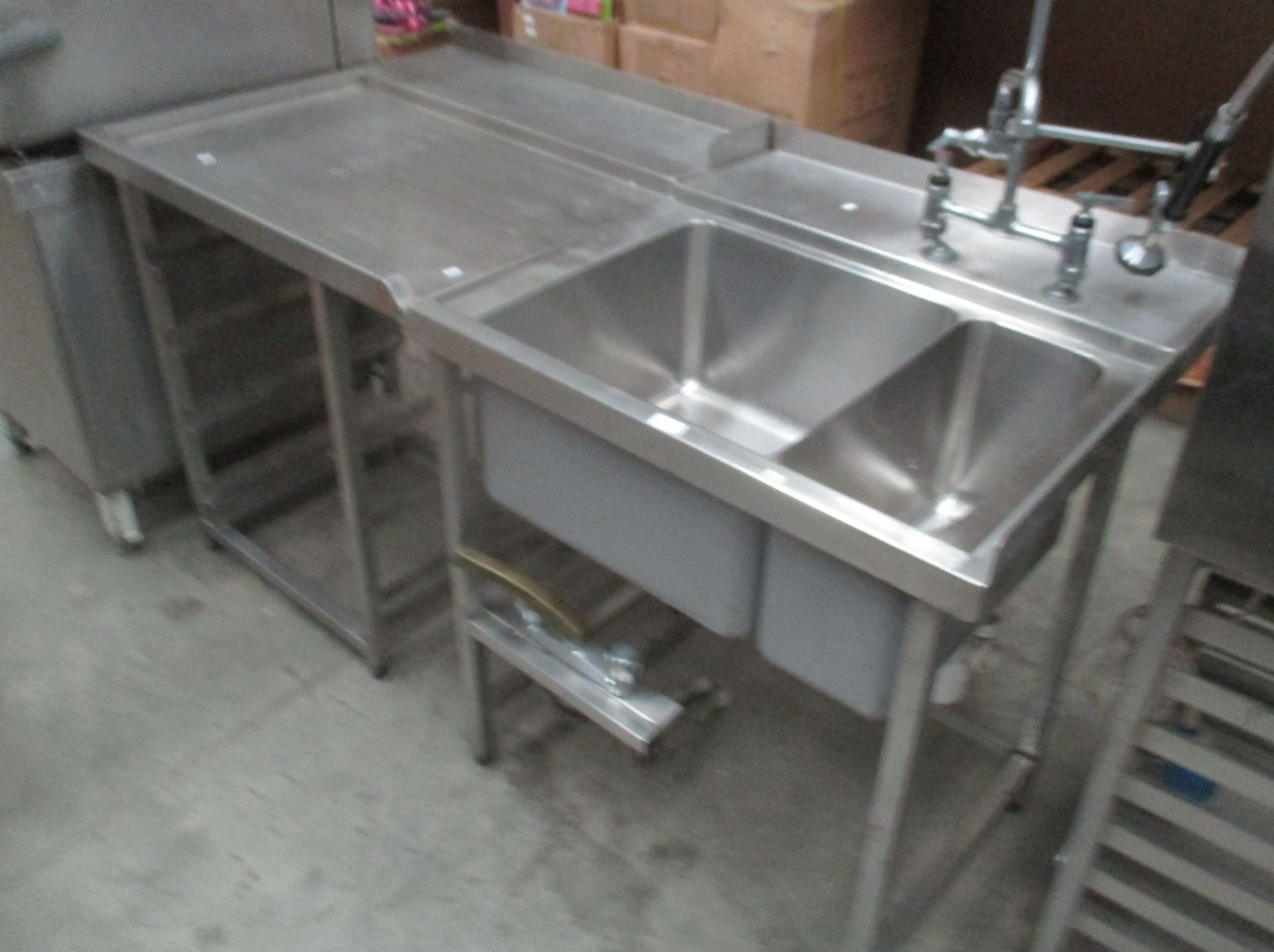 A stainless steel twin commercial sink with side drainer and double taps 80 x 160cm