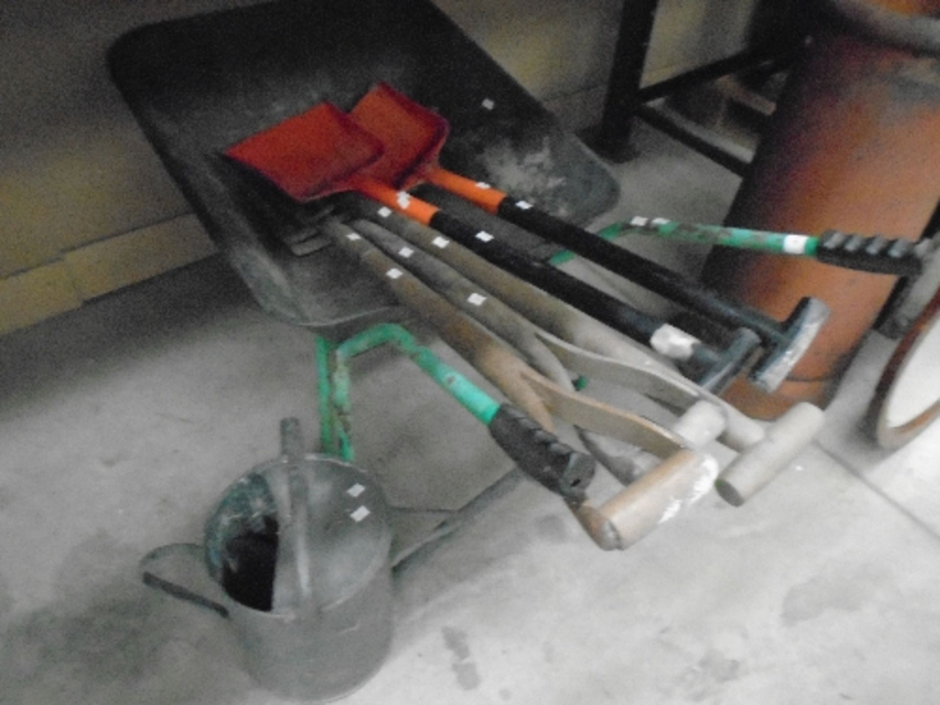 A green metal wheel barrow complete with metal watering can, spades, shovels, aluminium step ladder,