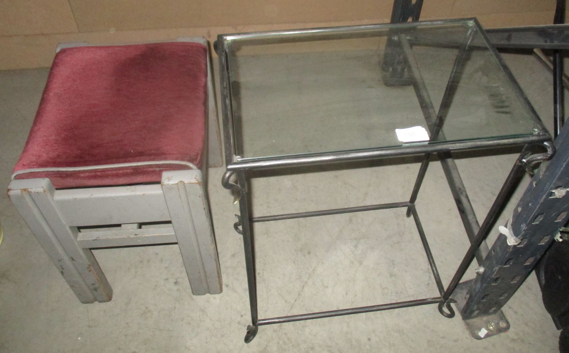 A wrought iron framed glass top side table and a red upholstered stool