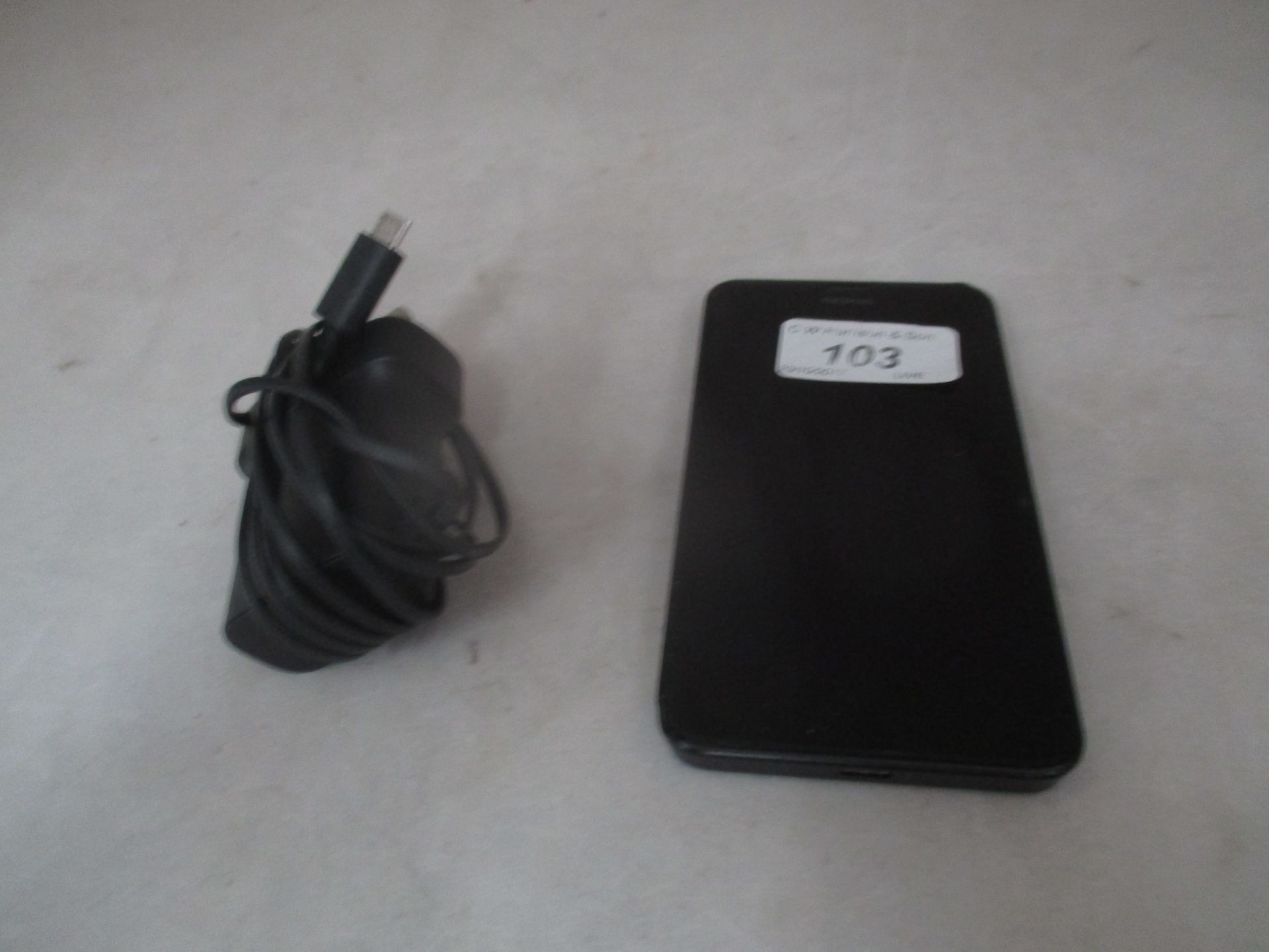 A Nokia Lumia RM-974 Microsoft mobile phone with charger