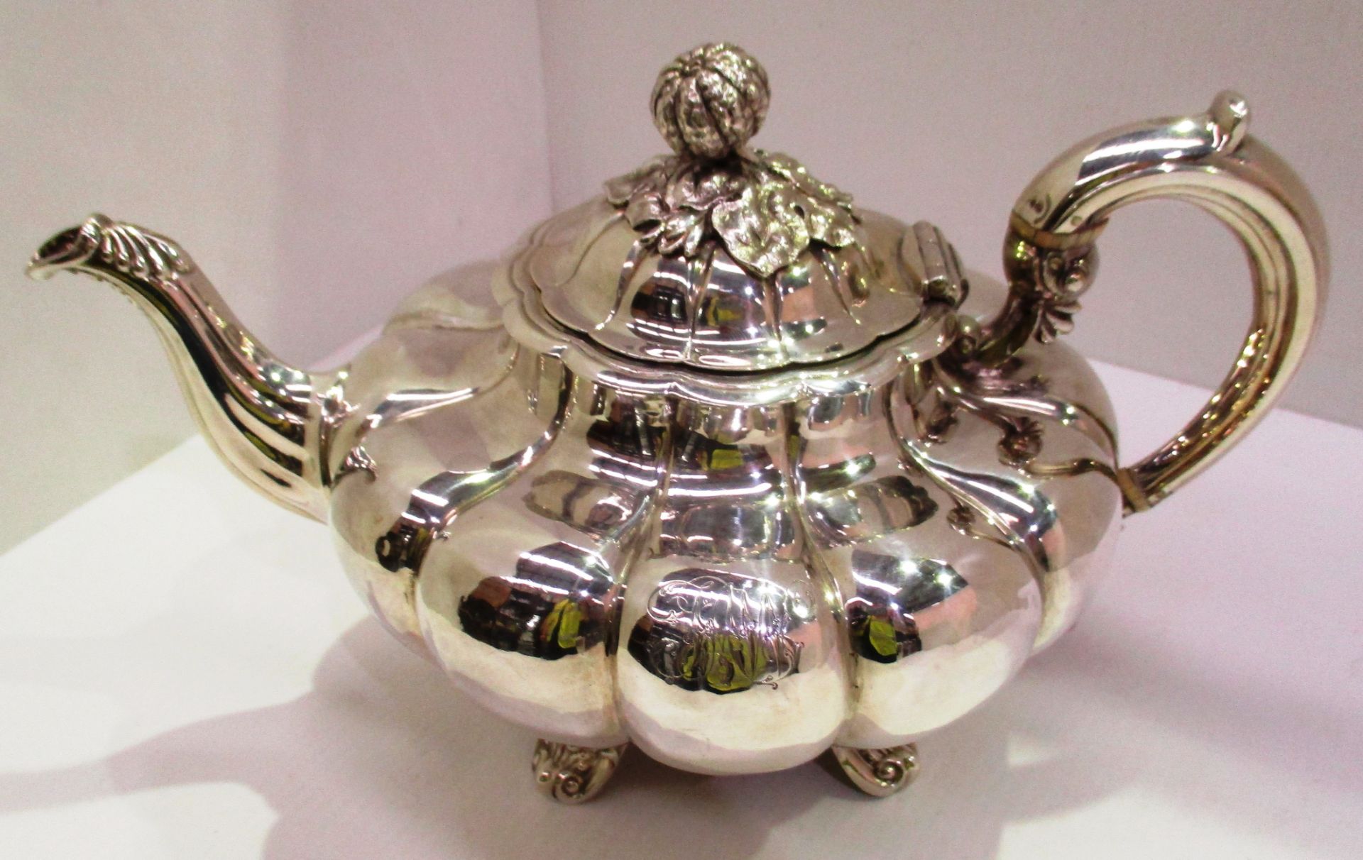 An early Victorian silver teapot of compressed fluted melon form, cast melon finial,