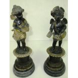 A pair of cast metal cherub figures on faux marble bases