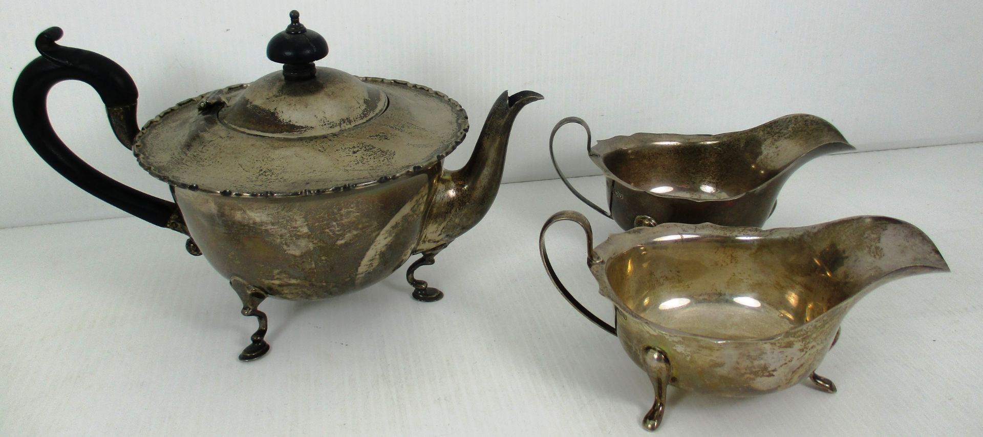 A silver tea pot with shaped rim, ebonised scroll handle, on 3 feet, 13cm high,