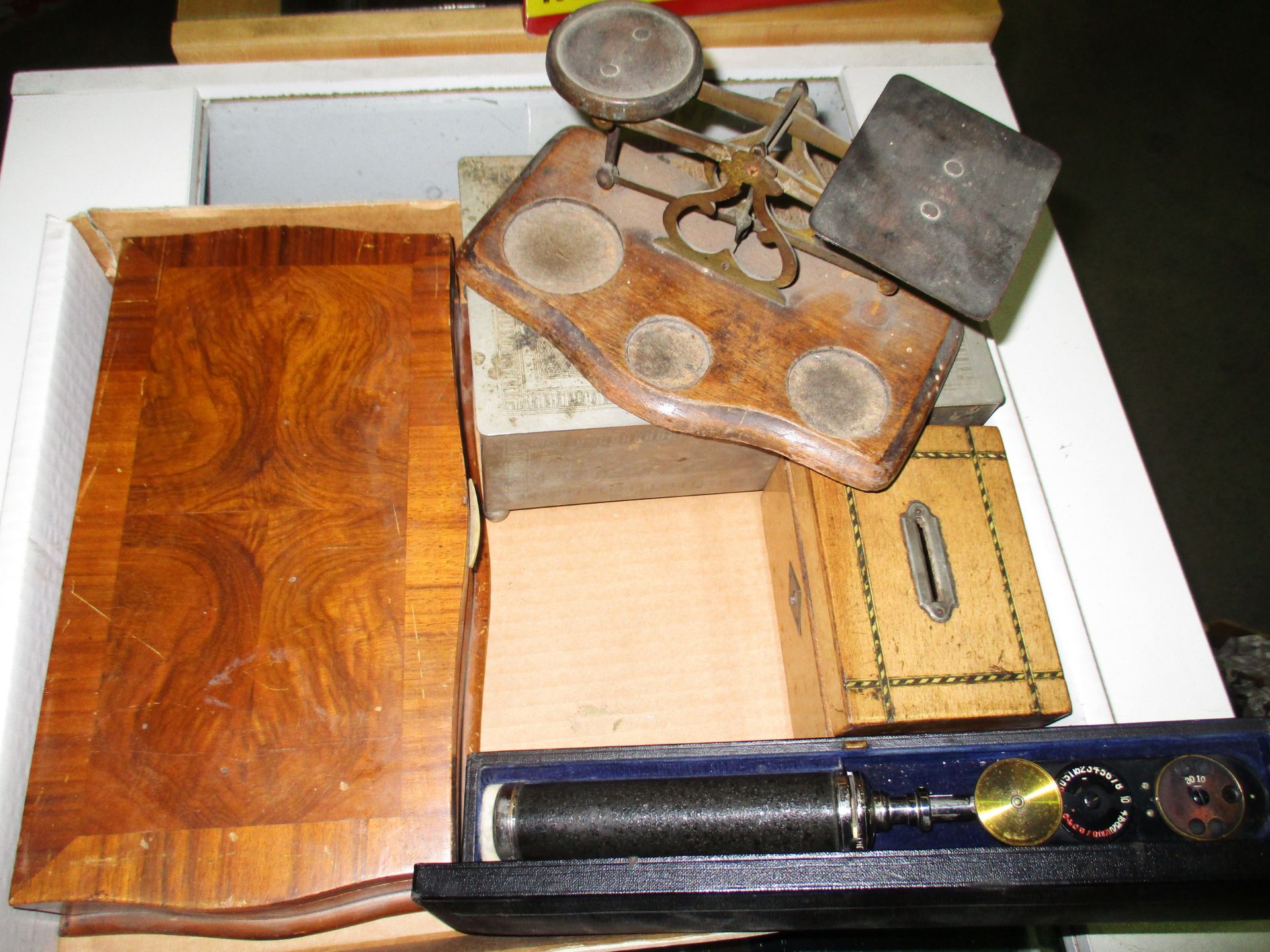 A pair of brass and wooden postal scales, a wooden money box, an optical tool, a wooden box,
