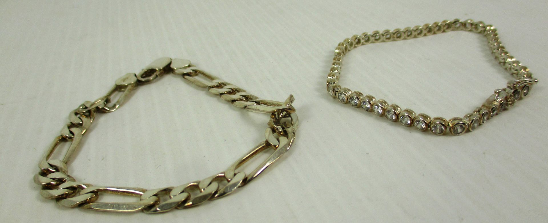 A silver flat link bracelet and another silver bracelet set with cubic Zirconia
