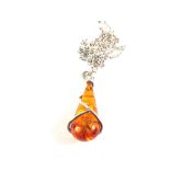 An Amber drop pendant mounted in white metal on Silver chain