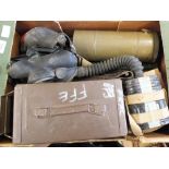 A box of military equipment including US entrenching tool, gas masks, ammo tin, holster, radio,