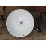 A round ceramic bathroom sink with chrome tap,