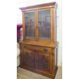 An Edwardian oak cupboard bookcase with carved doors