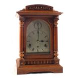 An Edwardian carved Oak striking mantel clock with chased silvered dial