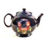 A Moorcroft Pansy pattern teapot on blue ground,