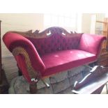 A Victorian mahogany scroll end settee with carved leaf back and maroon button back upholstery on