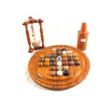 A wooden solitaire board with various stone balls,