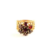 A large 9ct Gold ring with pierced shoulder details, large Garnet set flower cluster to top,