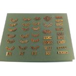 A collection of military buttons and brass shoulder titles including WWI and WWI examples mounted