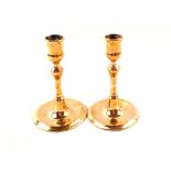 A pair of early 18th Century dwarf brass candlesticks with tulip shaped sconces and dished circular