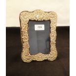 A silver photo frame with relief bird and floral decoration