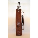 A vintage leather golf bag with five clubs