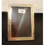 A rectangular silver photo frame with flower decoration (as found) and an oval silver photo frame