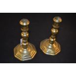 A pair of early 18th Century seamed brass candlesticks with knopped stems and octagonal bases,