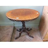 An oval mahogany and walnut occasional table on ornately carved column and quadricle supports