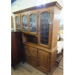 A modern oak dresser with lead and brass glazed doors above drawer and cupboard base