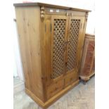 A pine cabinet with slatted folding doors