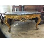 A carved gilt wood coffee table with a shaped variegated marble top