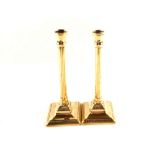 A pair of 18th Century brass candlesticks with fluted cylindrical stems and beaded square bases,