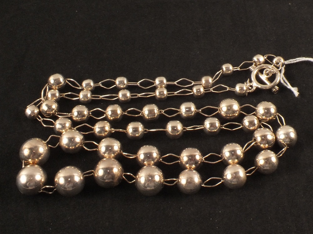 A long silver necklace with ball and link chain