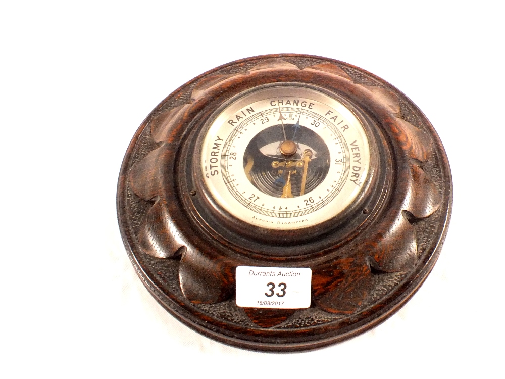 A circular carved oak barometer