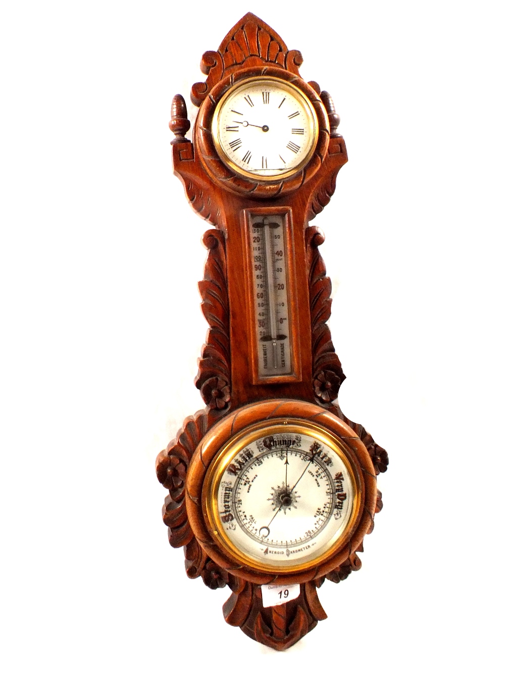 An aneroid barometer with clock in carved oak case (one hand detached)