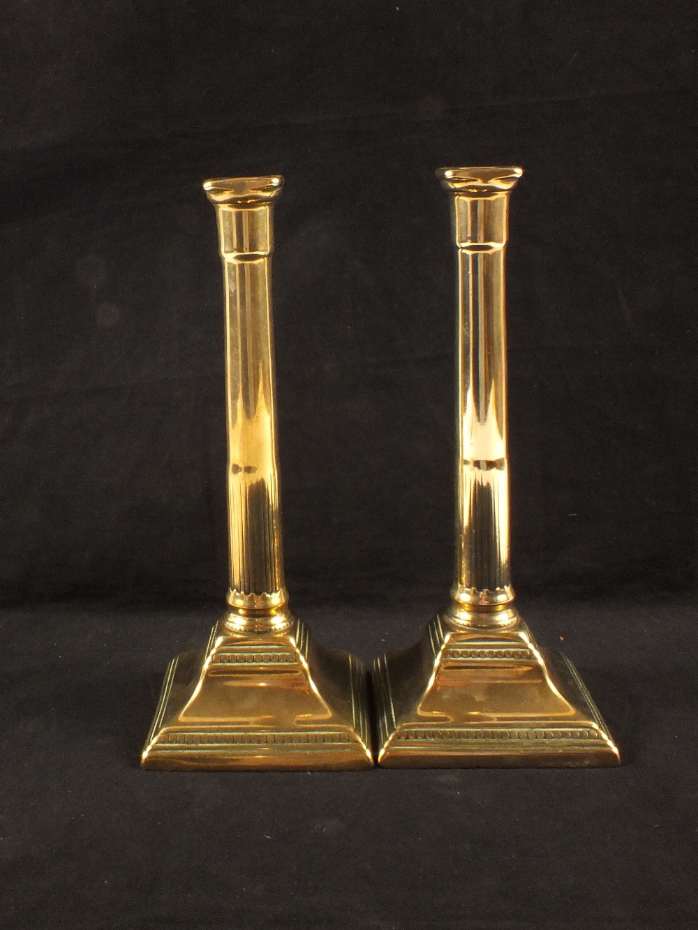 A pair of 18th Century brass candlesticks with part fluted cylindrical stems and beaded square