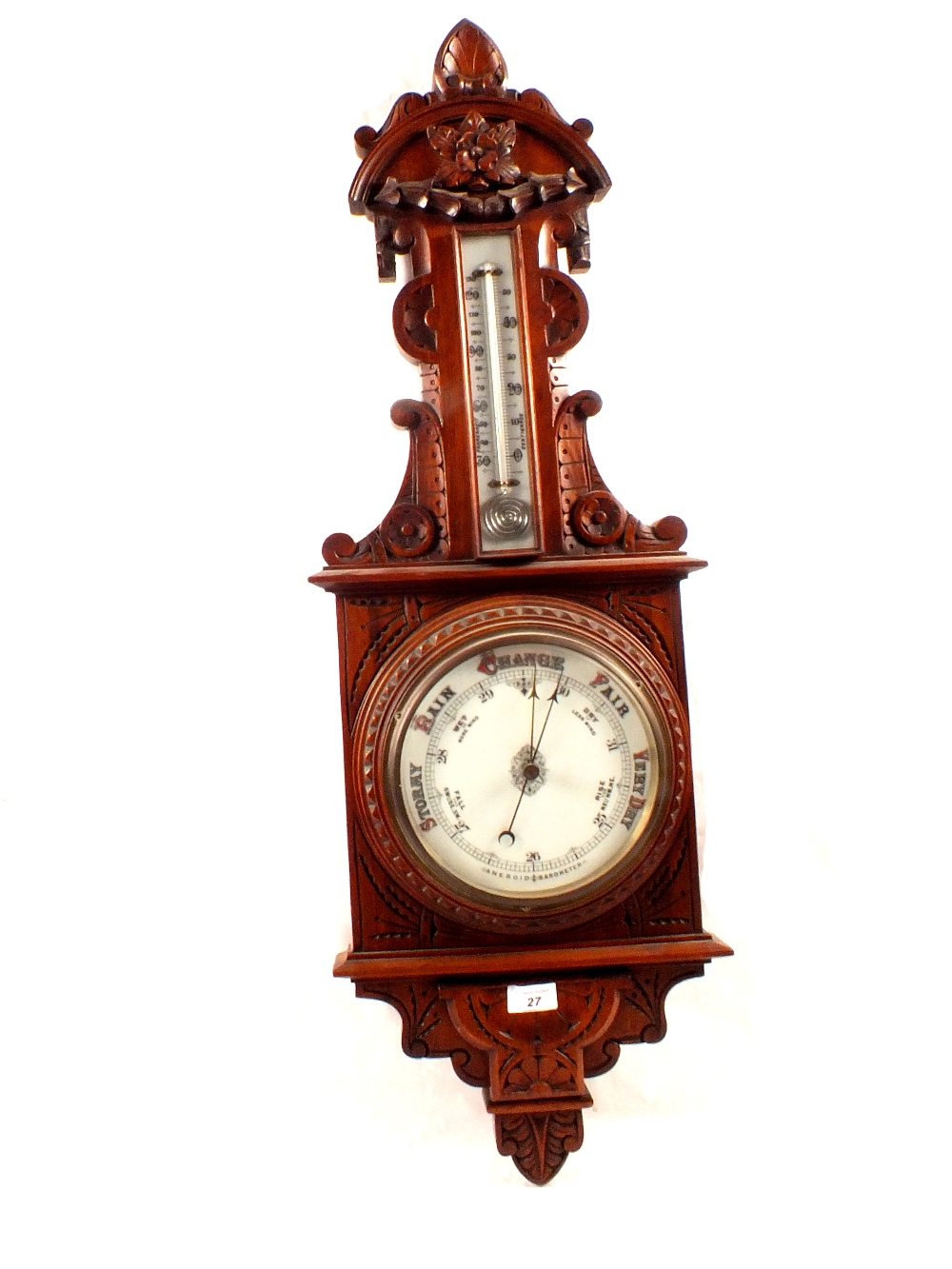 An aneroid barometer in heavily carved mahogany case