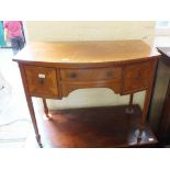 A reproduction inlaid mahogany three drawer kneehole bow front desk on square tapered feet