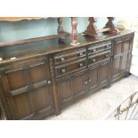 A long dark Ercol sideboard with four drawers and four cupboards